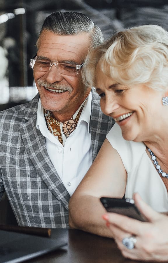 Well dressed mature couple sitting outside at a restaurant looking at a computer together