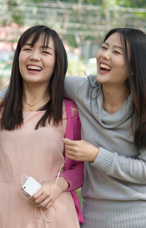 Two women in a park holding each other and laughing